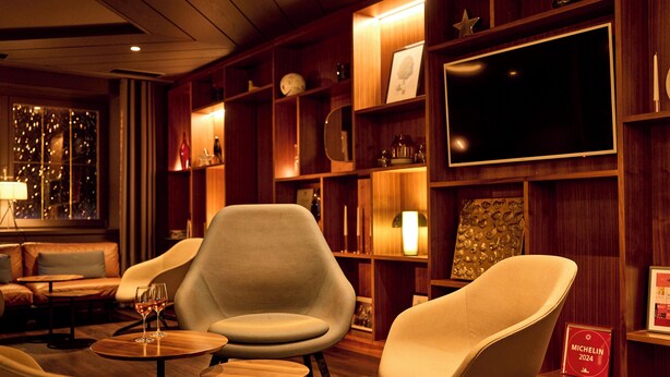 A cozy lounge area with comfortable seating, a flat-screen TV, and a wine glass on a small table. - Hotel Gasthof Zum Bad (Langenau)