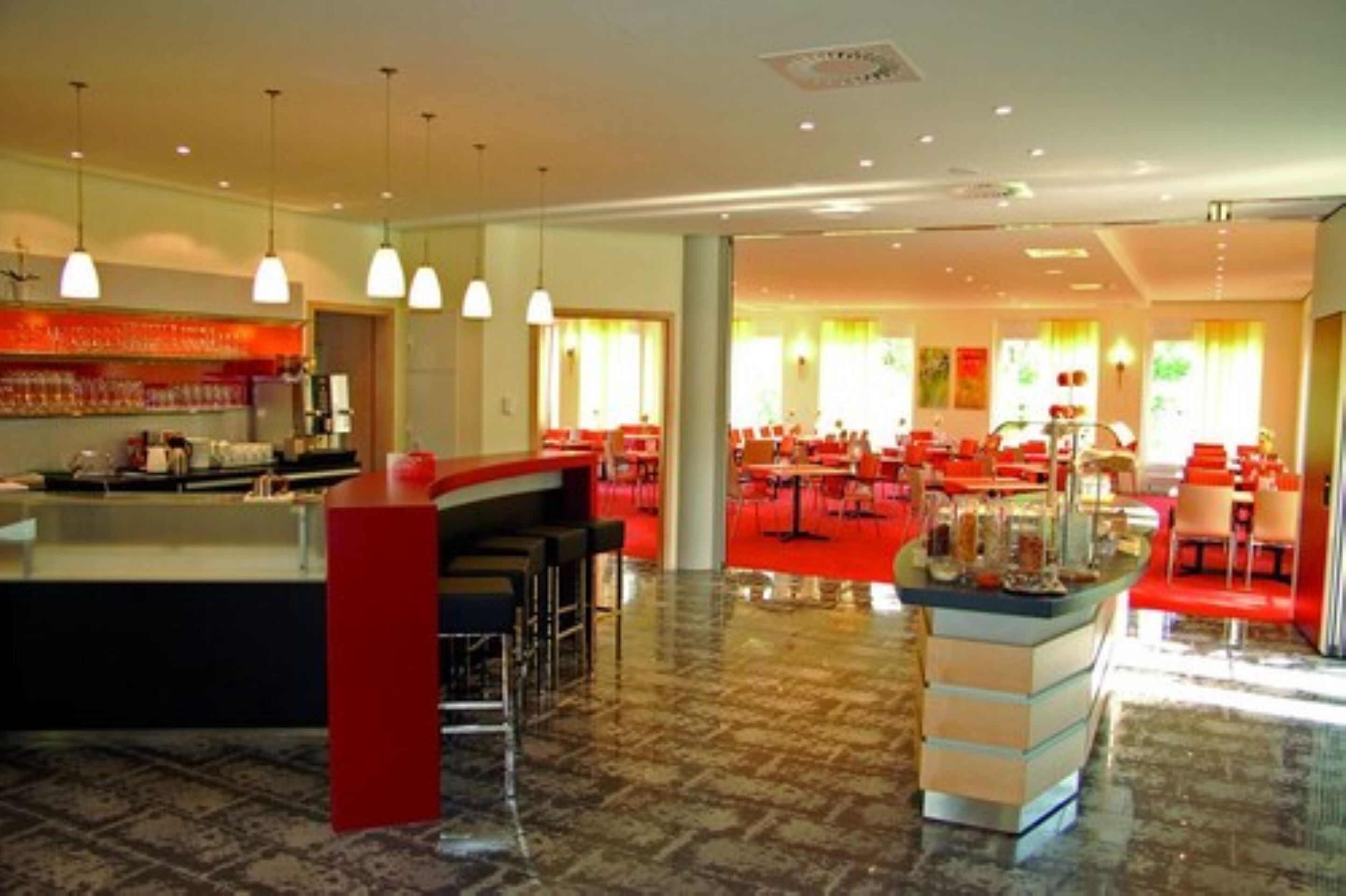 A spacious hotel lobby with a central bar area, multiple seating arrangements, and a modern design.