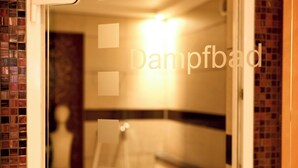 A bathroom with a tiled wall, a shower area, and a mirror. - Hotel Gasthof Zum Bad (Langenau)