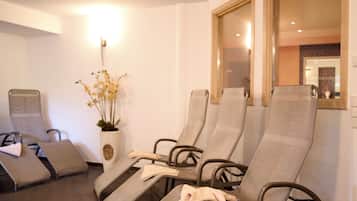 A room with reclining chairs, a potted plant, and a mirror on the wall.