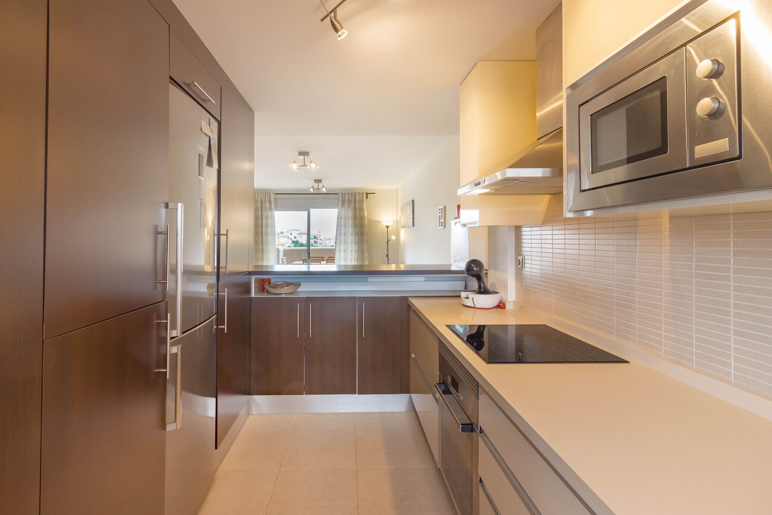 A modern kitchen with stainless steel appliances, a built-in oven, and a large window.