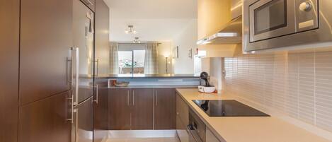 A modern kitchen with stainless steel appliances, a built-in oven, and a large window.