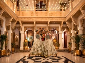 A grand hall with ornate columns, a patterned floor, and decorative lighting. - Guleria Kothi (Varanasi)
