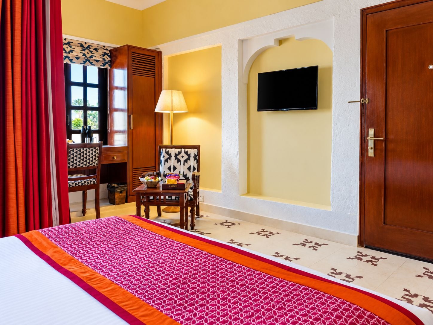 Una habitación de hotel con una cama, un escritorio, una silla, un televisor y una puerta.