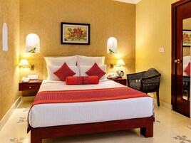 A hotel room with a large bed, two bedside tables, a chair, and a door.