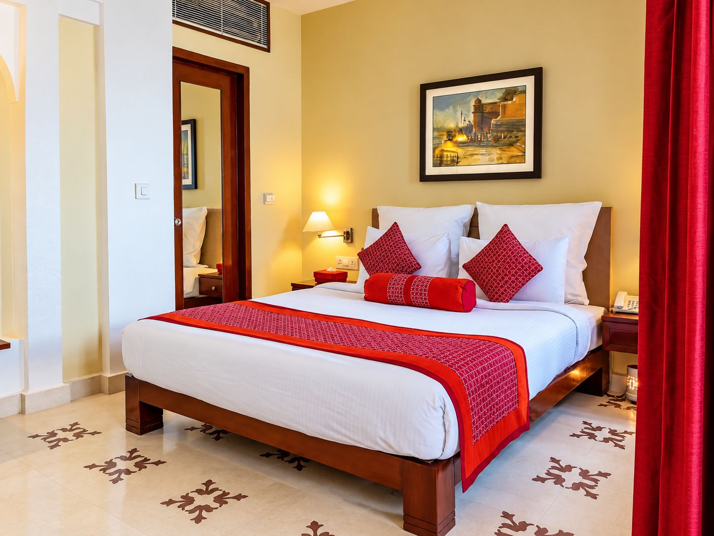 Una habitación de hotel con una cama grande, un cuadro en la pared y una cortina roja.