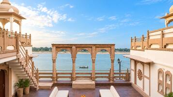 A terrace with a view of a river, a gazebo, and a seating area with a table.