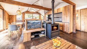 A cozy, wood-furnished living area with a fireplace, a dining table, and a TV. - MOULIN III - Luxury chalet with private hot tub (Les Gets)