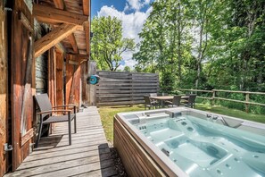 Una terraza de madera con un jacuzzi, una silla y una mesa.