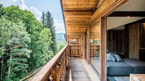 A wooden balcony with a view of dense forest and mountains. - MOULIN II - Design chalet with private hot-tub (Les Gets)