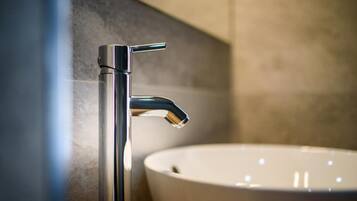 Ein Badezimmer mit einem modernen Waschbecken und einem chromfarbenen Wasserhahn.