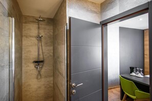 A modern bathroom with a shower, a dark door, and a small table with a chair. - ORA Luxury Rooms (Dubrovnik)