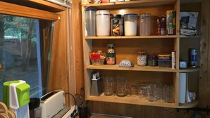 A kitchen with wooden shelves stocked with jars, containers, and kitchen utensils. - Ferienhaus Mirow-Lärz - Kamin Wald Ruhe (Laerz)