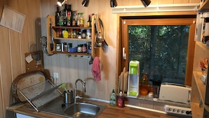 A kitchen with wooden cabinets, a stainless steel sink, a Bosch toaster, and a window with a view of trees. - Ferienhaus Mirow-Lärz - Kamin Wald Ruhe (Laerz)