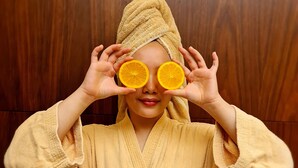 A person in a yellow robe with a towel wrapped around their head, standing in front of a wooden background. - Souq Al Wakra Hotel Qatar by Tivoli (Al Wakrah)