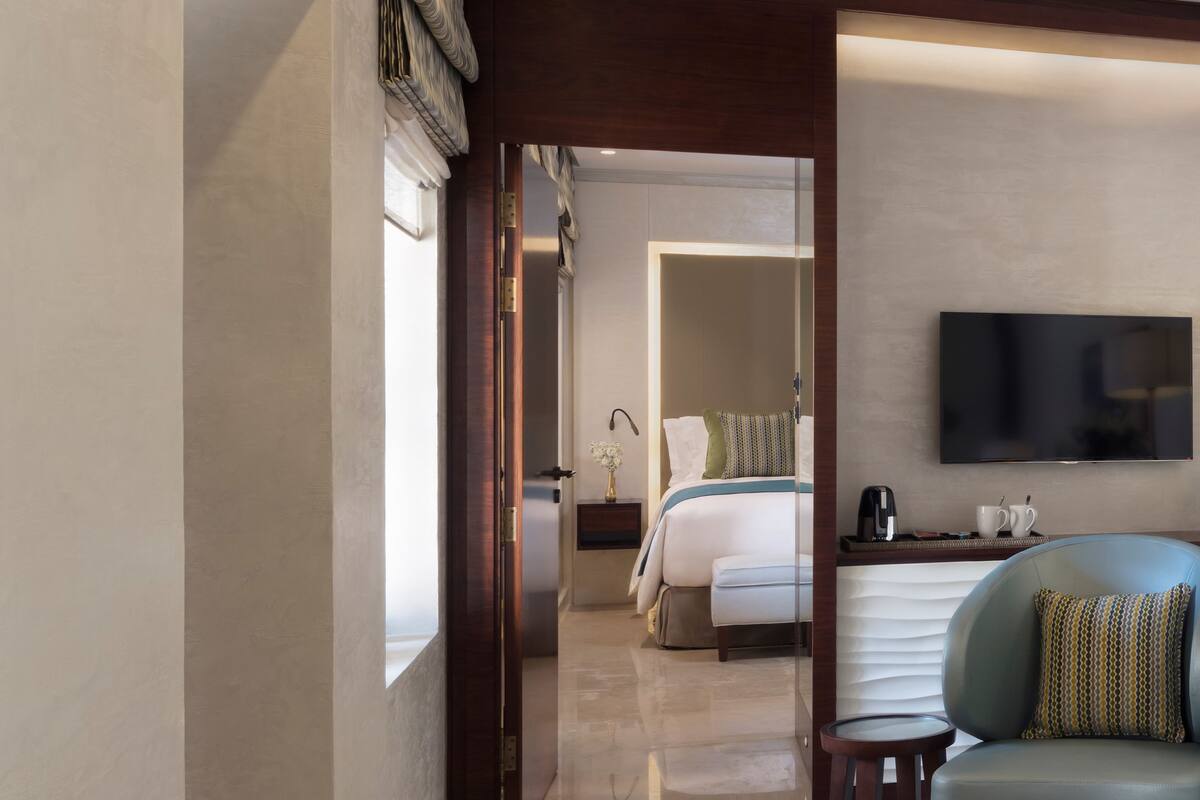 A modern hotel room with a bed, bedside table, and a flat-screen TV mounted on the wall.