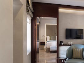 Habitación de hotel moderna con cama, mesita de noche y televisor de pantalla plana montado en la pared.
