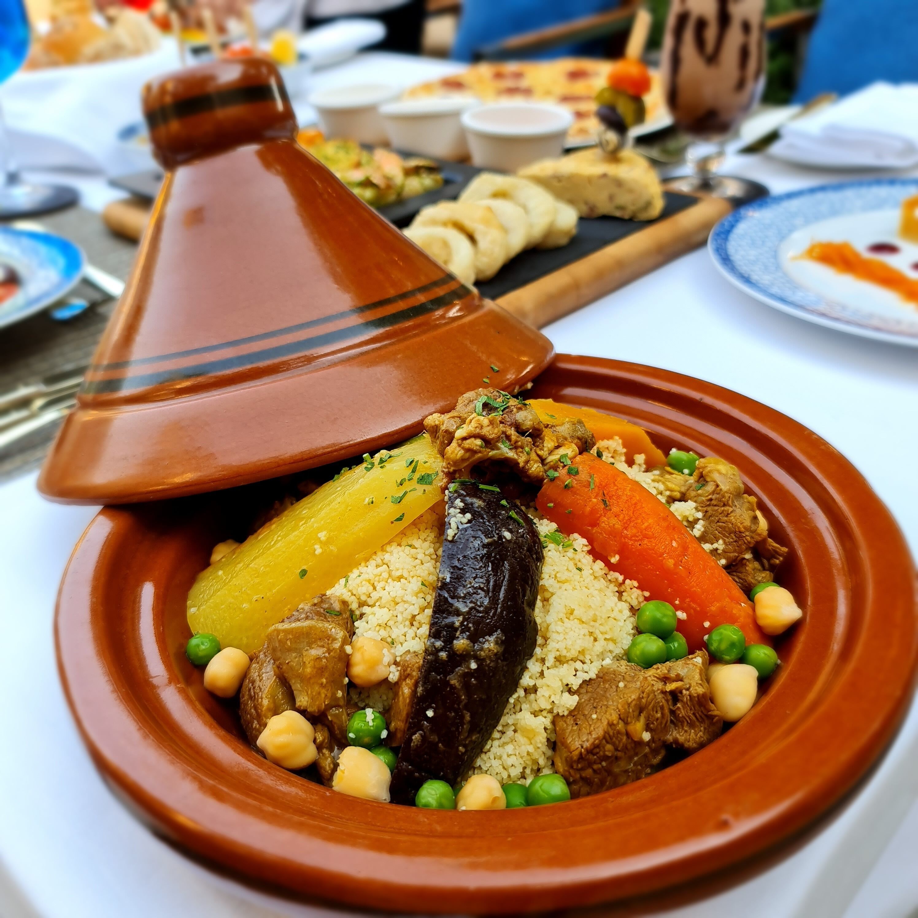 Ein traditionelles marokkanisches Tajine-Gericht mit Gemüse und Fleisch, serviert in einem Tongefäß.