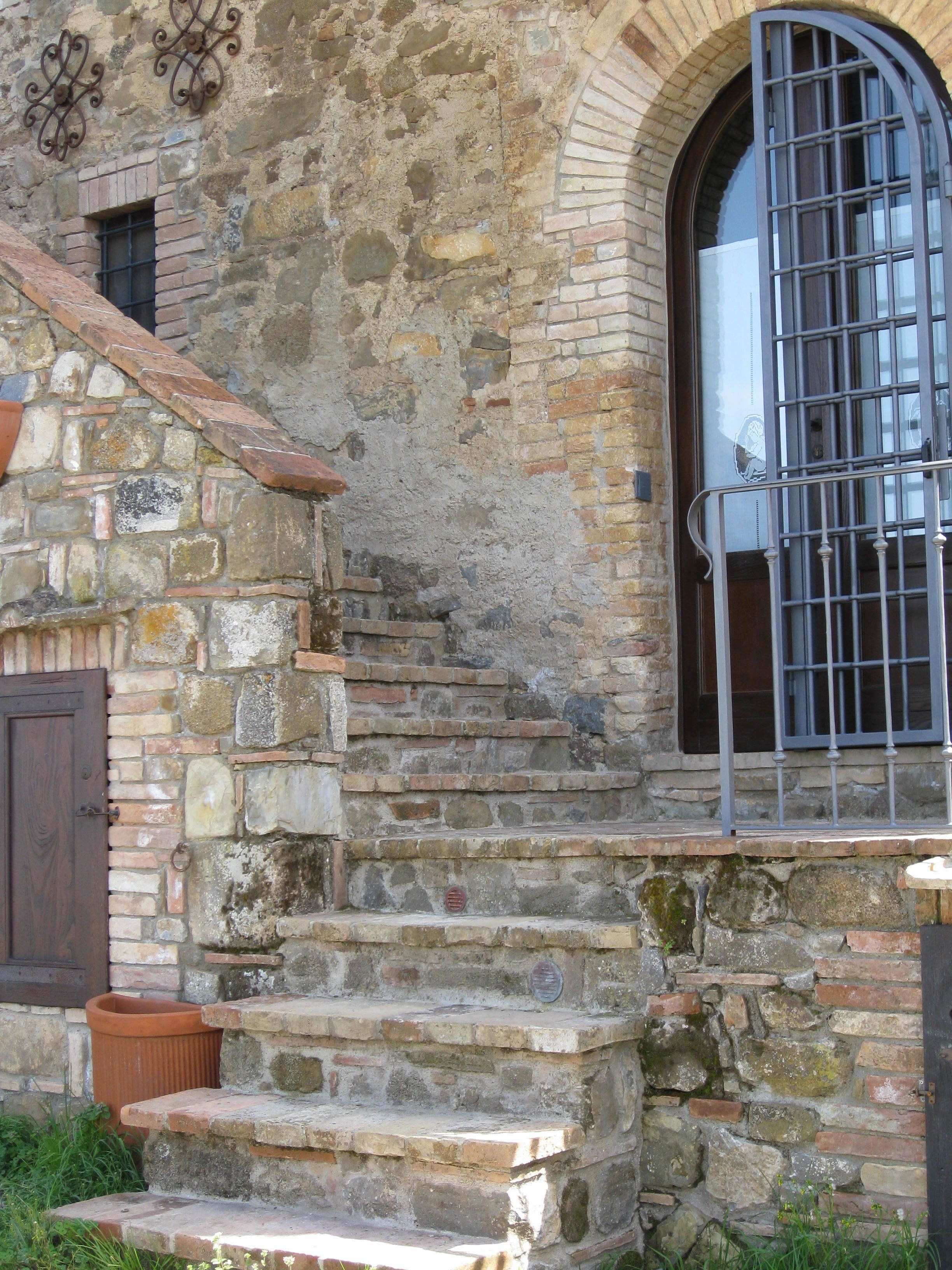 A stone staircase leading to a door with a metal gate.