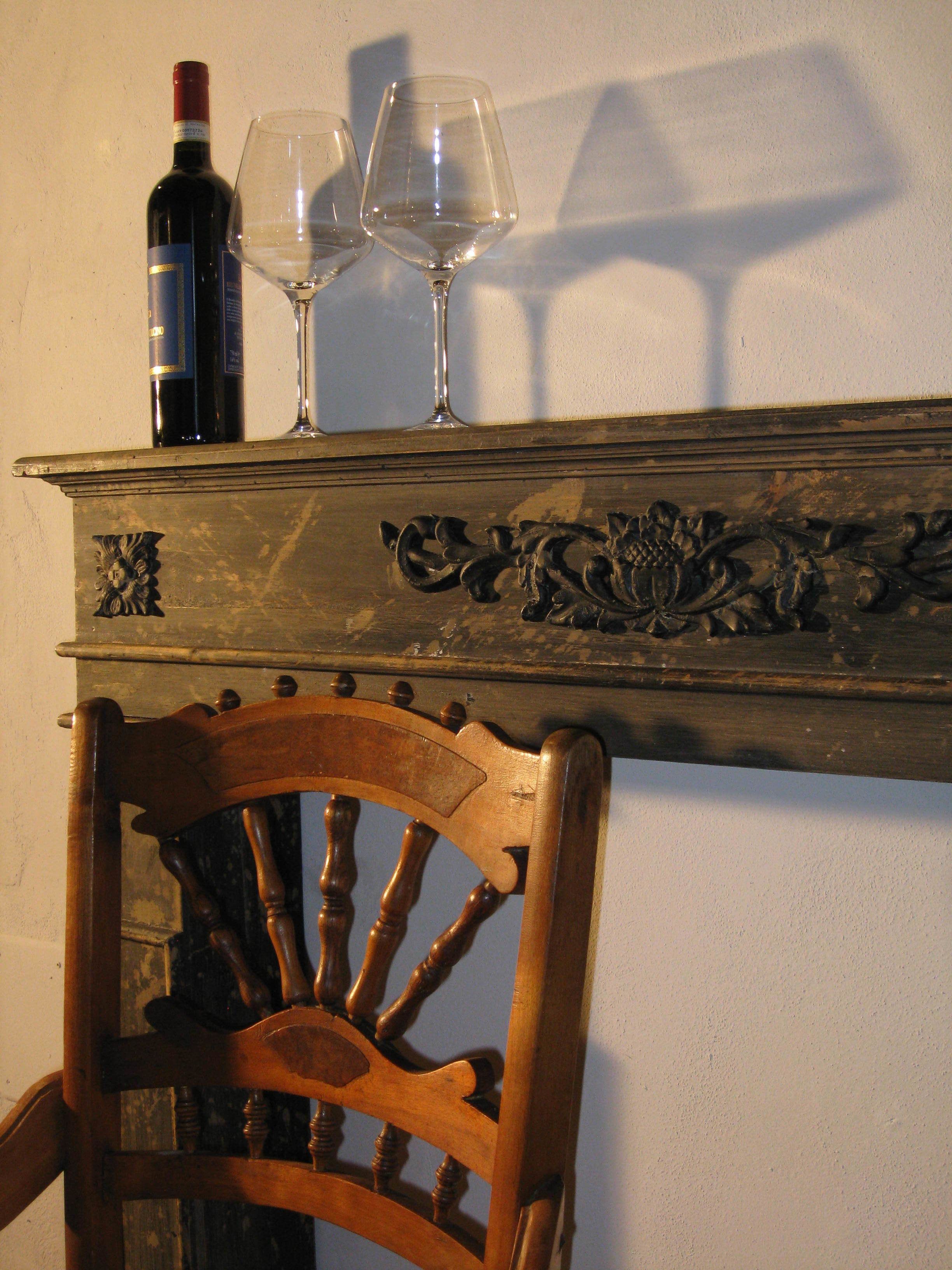 A wooden chair with a carved backrest and a decorative mantelpiece above it.