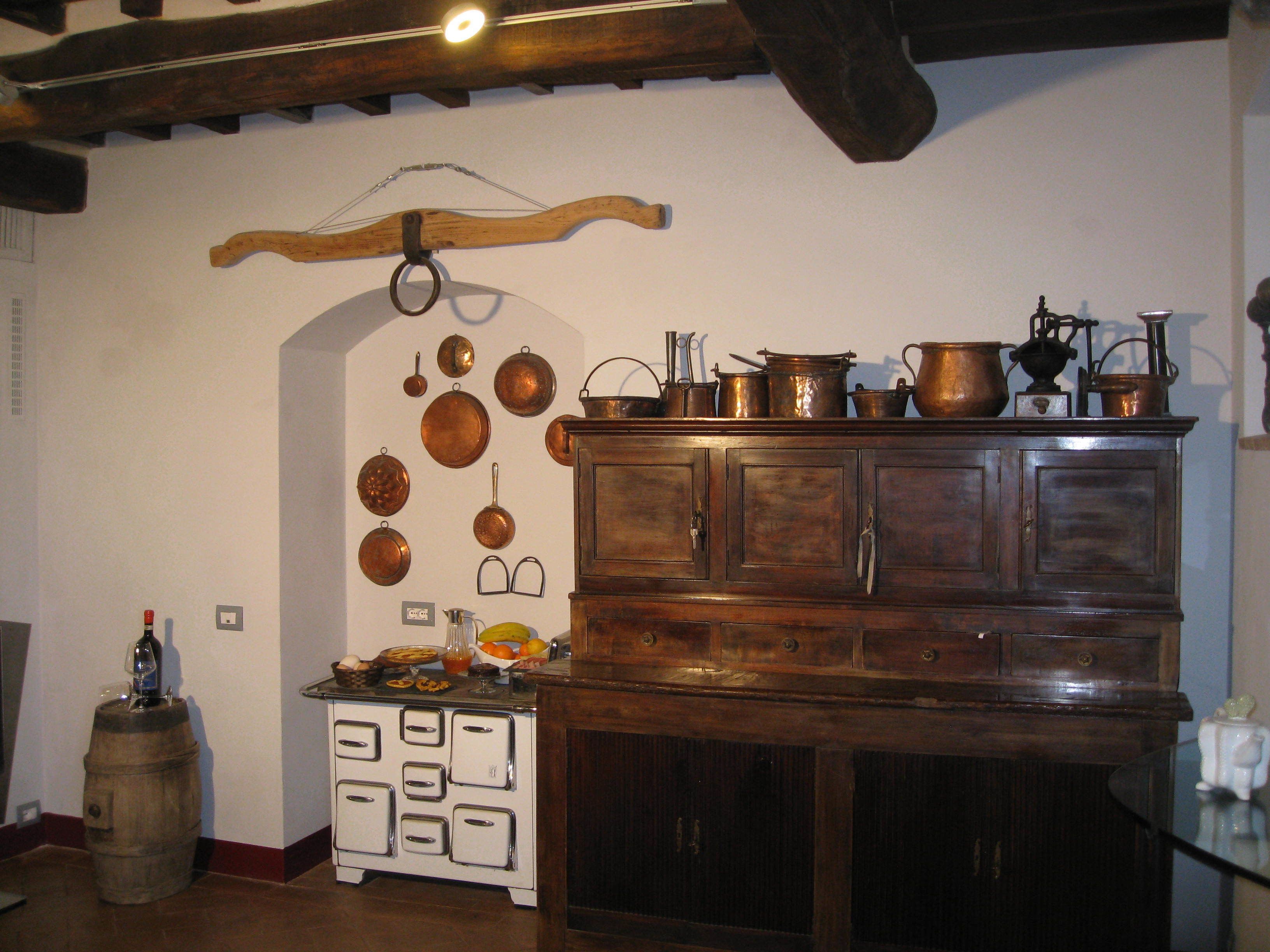 A kitchen with a wooden cabinet, a vintage stove, and various kitchen utensils hanging on the wall.