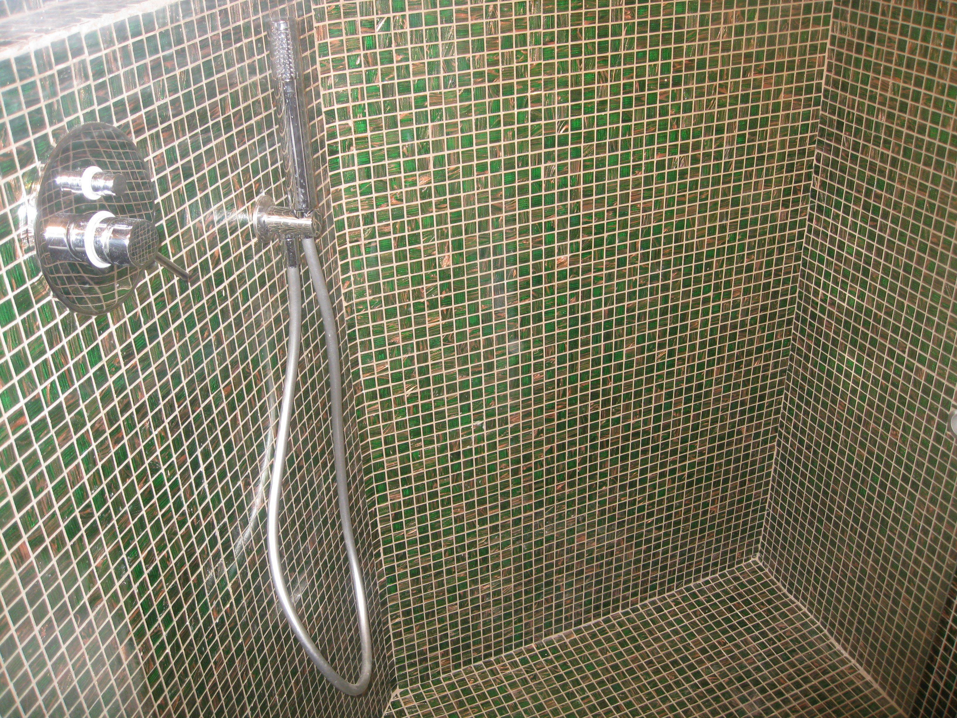 A shower area with a tiled wall and a showerhead.