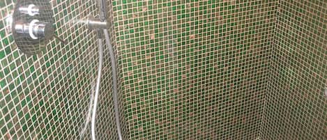 A shower area with a tiled wall and a showerhead.