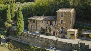 A stone building with a tiled roof, surrounded by greenery and a stone wall. - Il Burellino Wine & Resort (Montalcino)