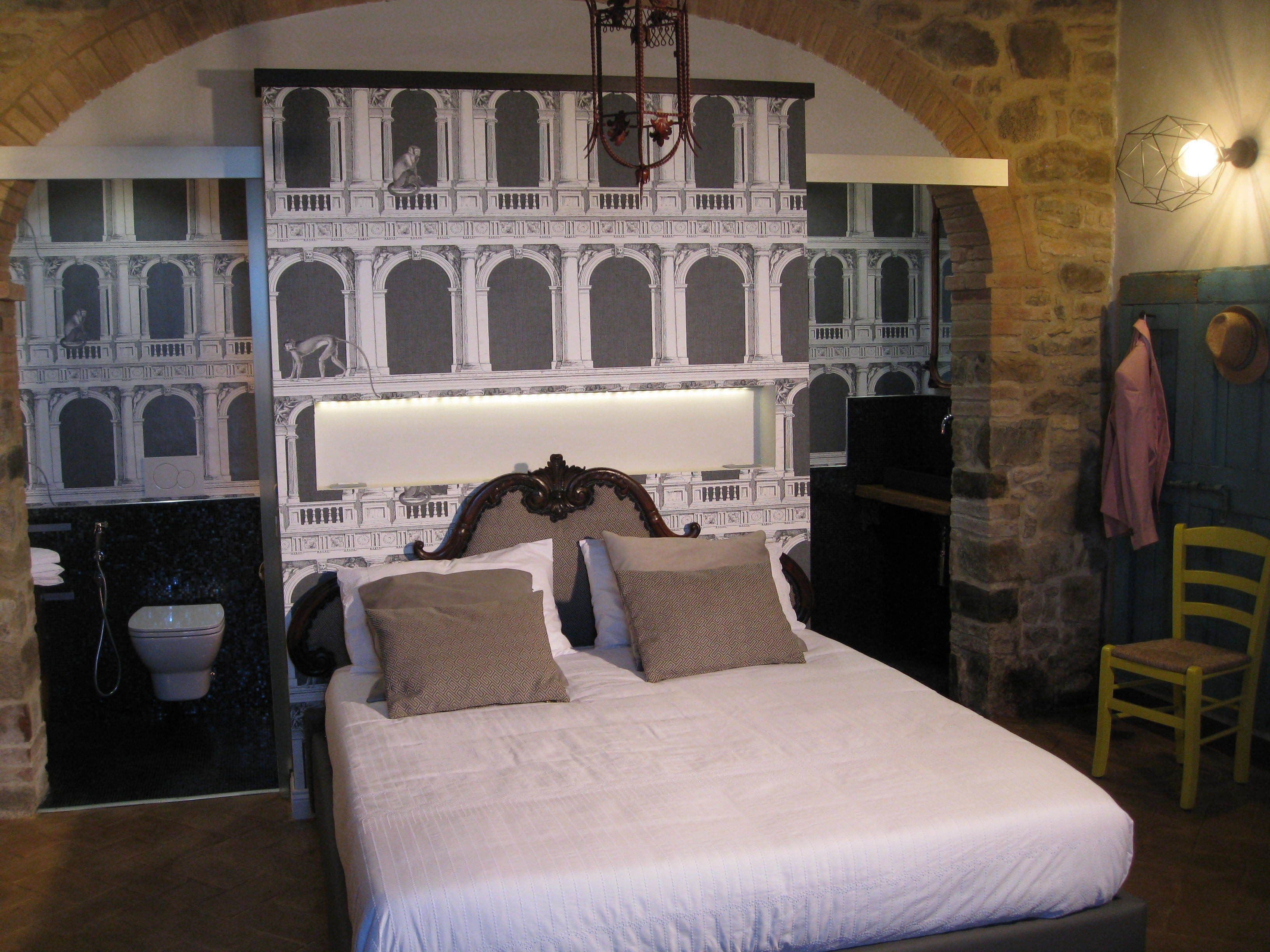Un dormitorio con una cama grande, una pared de piedra y un mural de un edificio clásico.