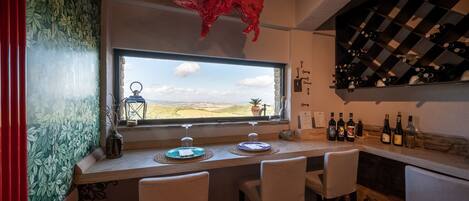 A bar area with a large window, a red bull decoration, and a wine rack.