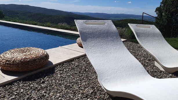 A poolside area with two lounge chairs and a woven ottoman. - Il Burellino Wine & Resort (Montalcino)