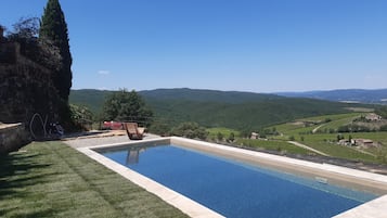 A swimming pool with a clear view of the surrounding landscape, including hills and vineyards.