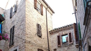 Una estrecha calle empedrada con edificios de piedra tradicionales, contraventanas de madera y un pequeño arco.