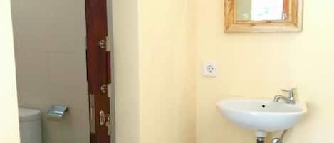 A bathroom with a white sink, a mirror, and a red trash bin.