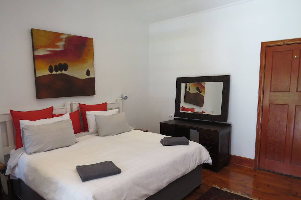 A bedroom with a bed, pillows, a TV on a stand, and a door.