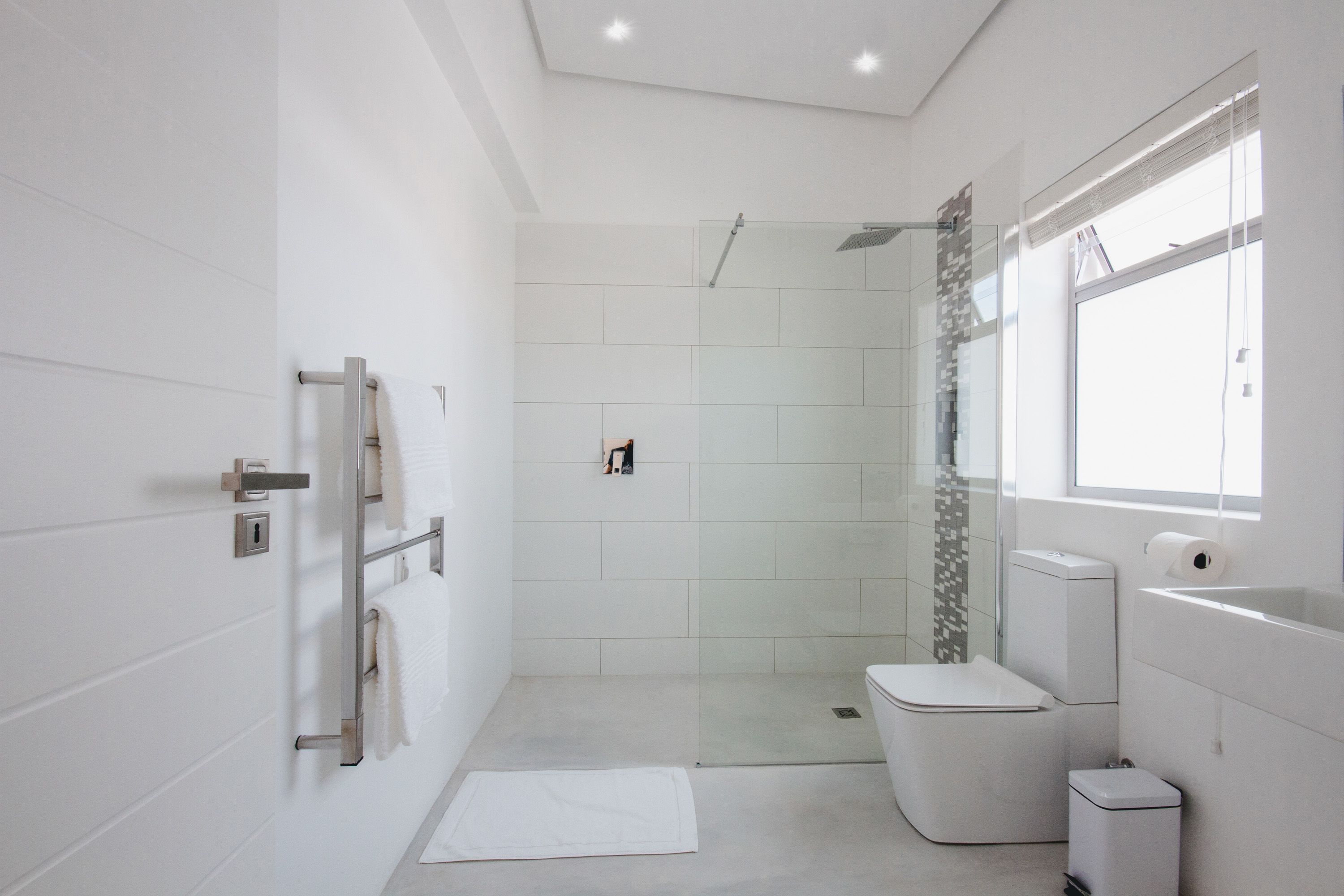 A modern bathroom with a glass-enclosed shower, a toilet, and a sink.