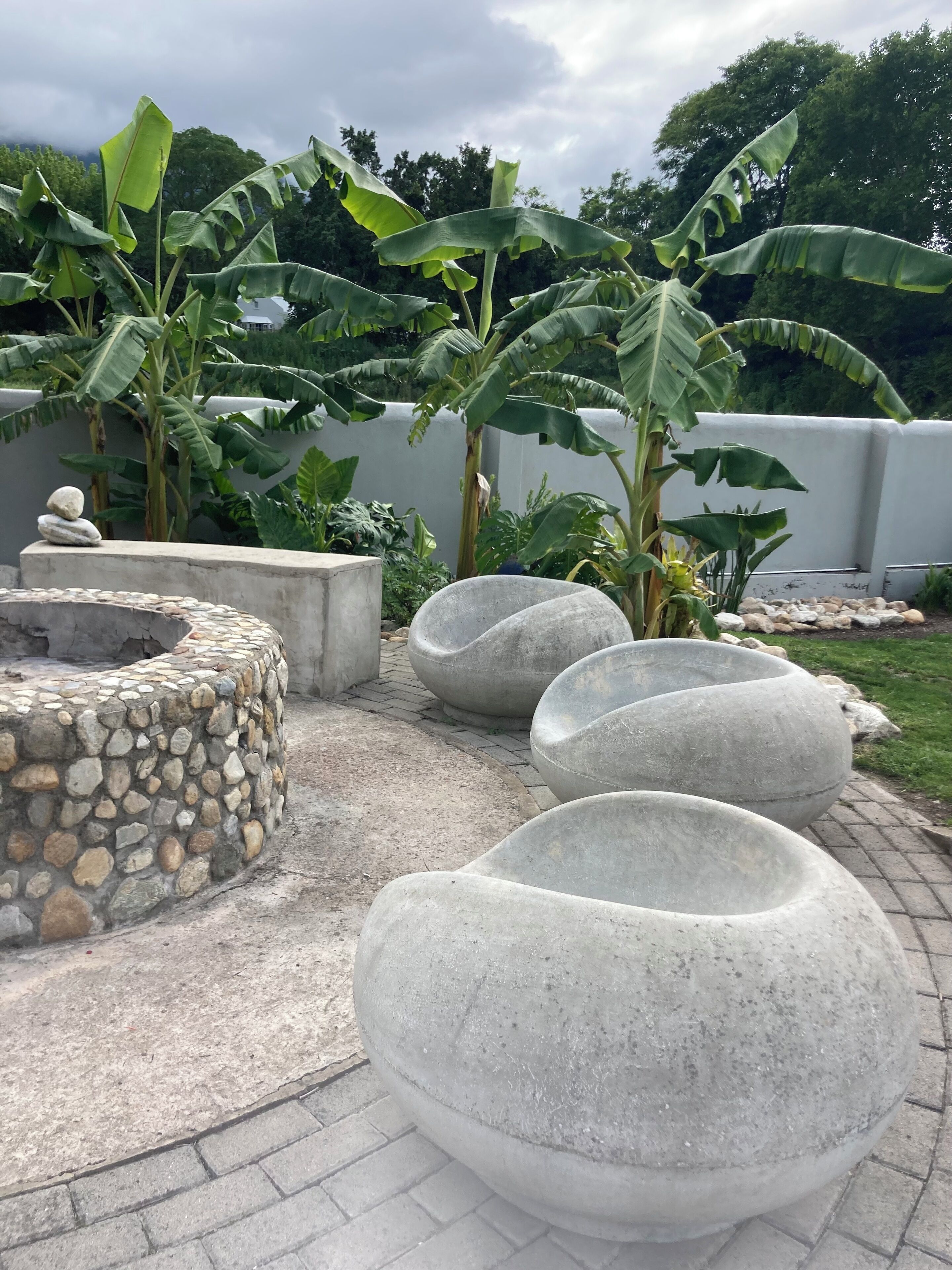 A garden with stone planters and banana plants.