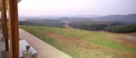 A balcony with a view of a forested valley and a clear sky.