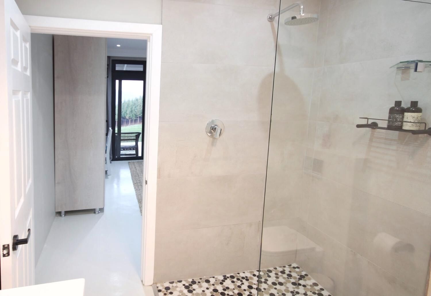 A modern bathroom with a glass shower enclosure, a tiled floor, and a visible shower head.