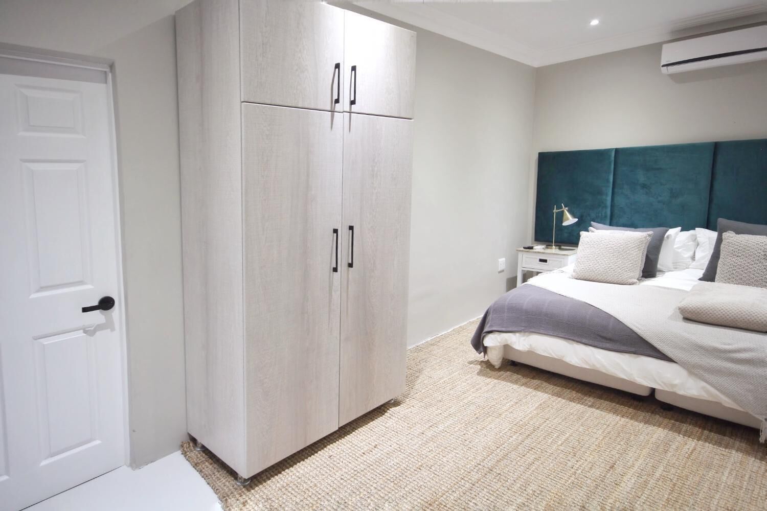 A bedroom with a bed, a wardrobe, a nightstand, and an air conditioning unit.