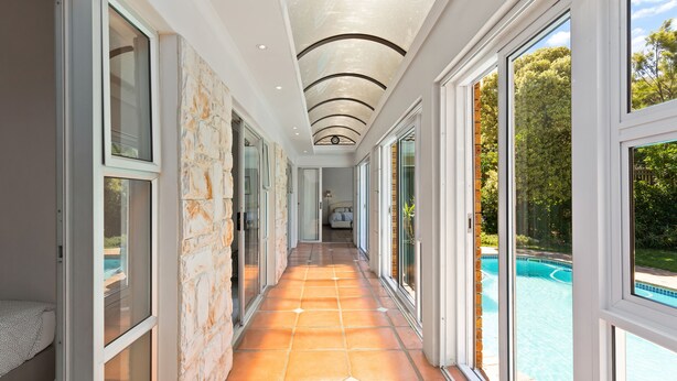 A corridor with large windows, a tiled floor, and a view of a swimming pool. - Hout Bay Hilltop - In Cape Town (Hout Bay) (Cape Town)