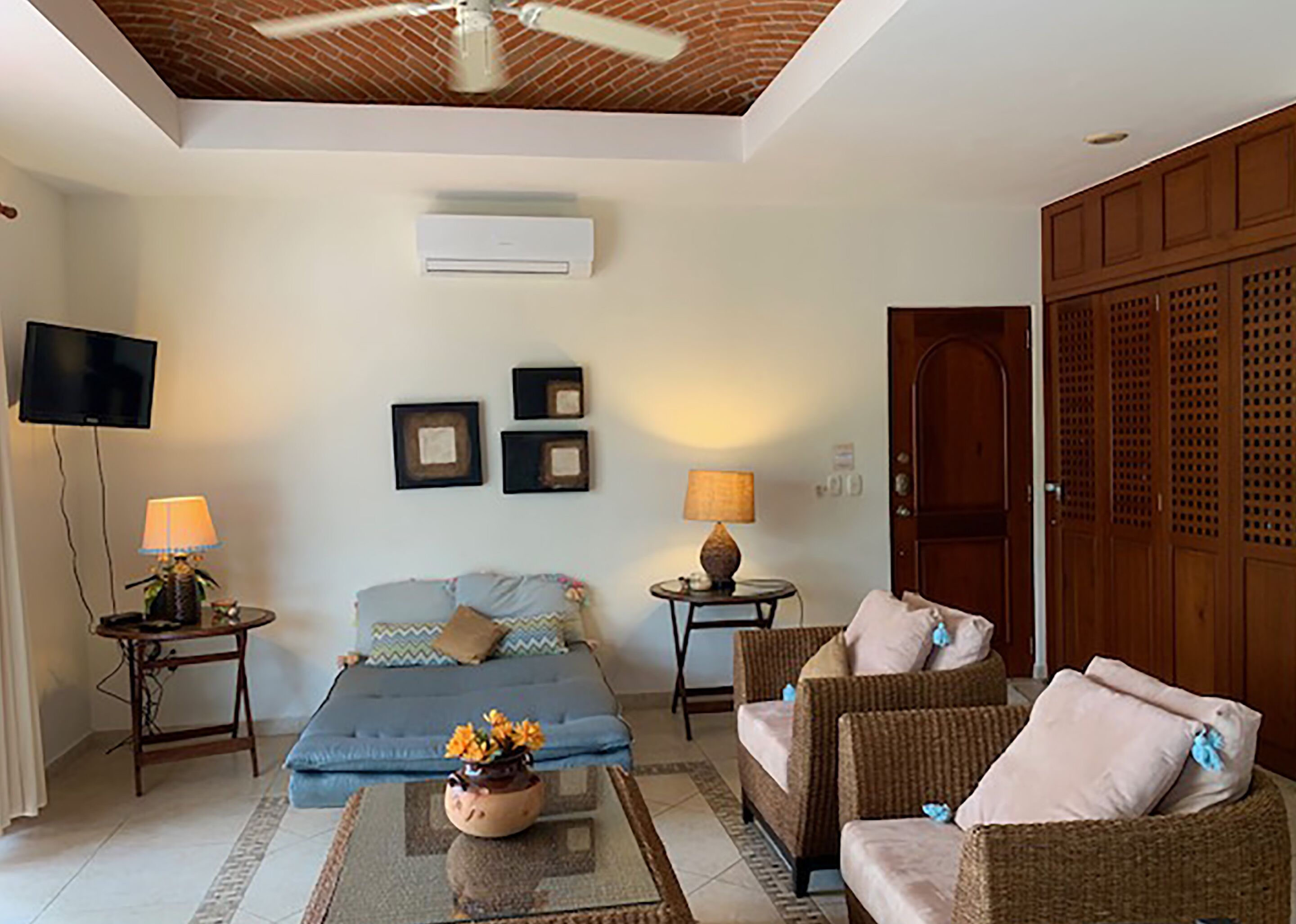 A living room with a sofa, two side tables with lamps, a coffee table, and a television mounted on the wall.