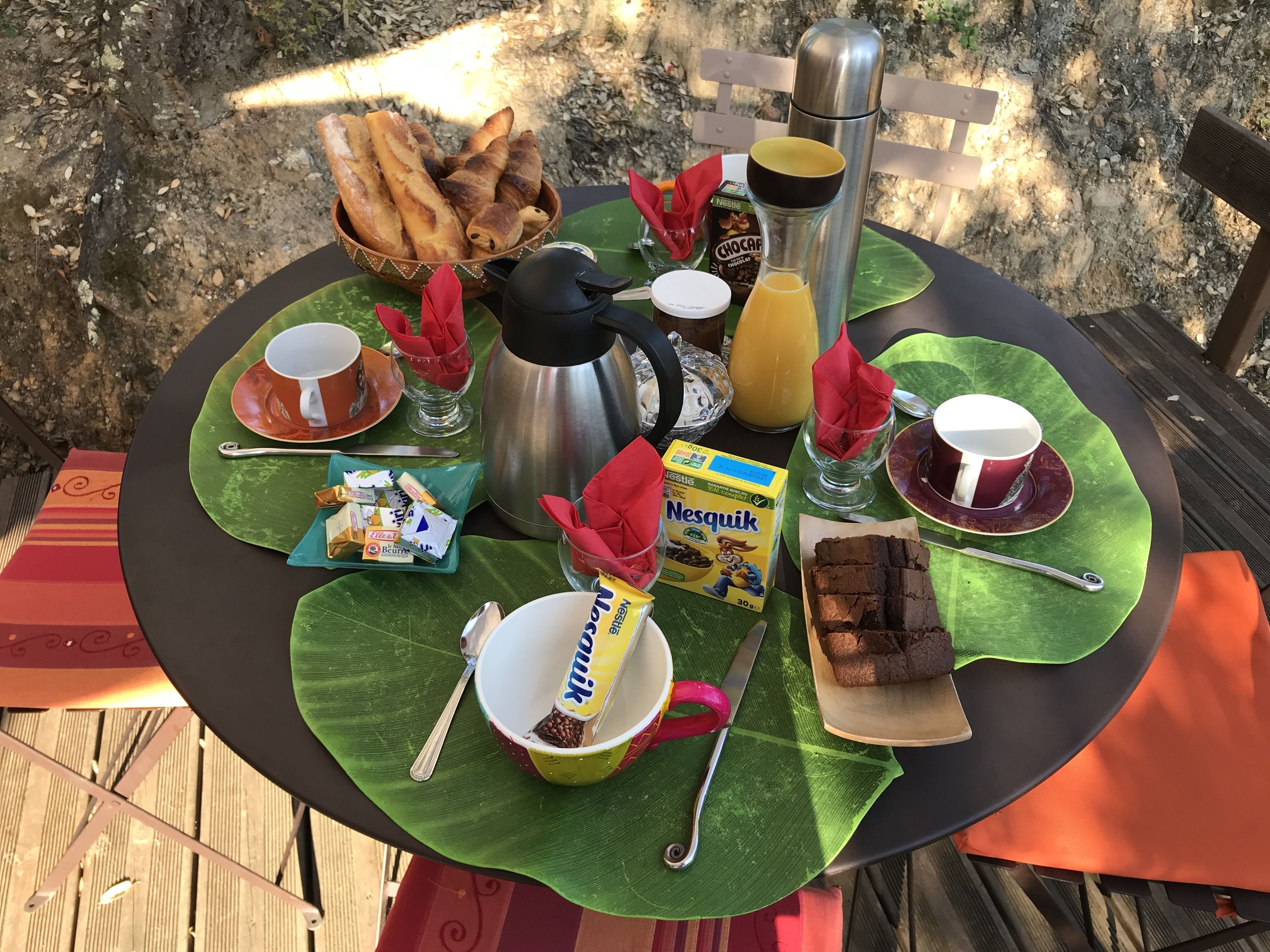 A table set with breakfast items including bread, coffee, juice, and snacks.