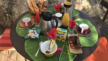 A table set with breakfast items including bread, coffee, juice, and snacks.