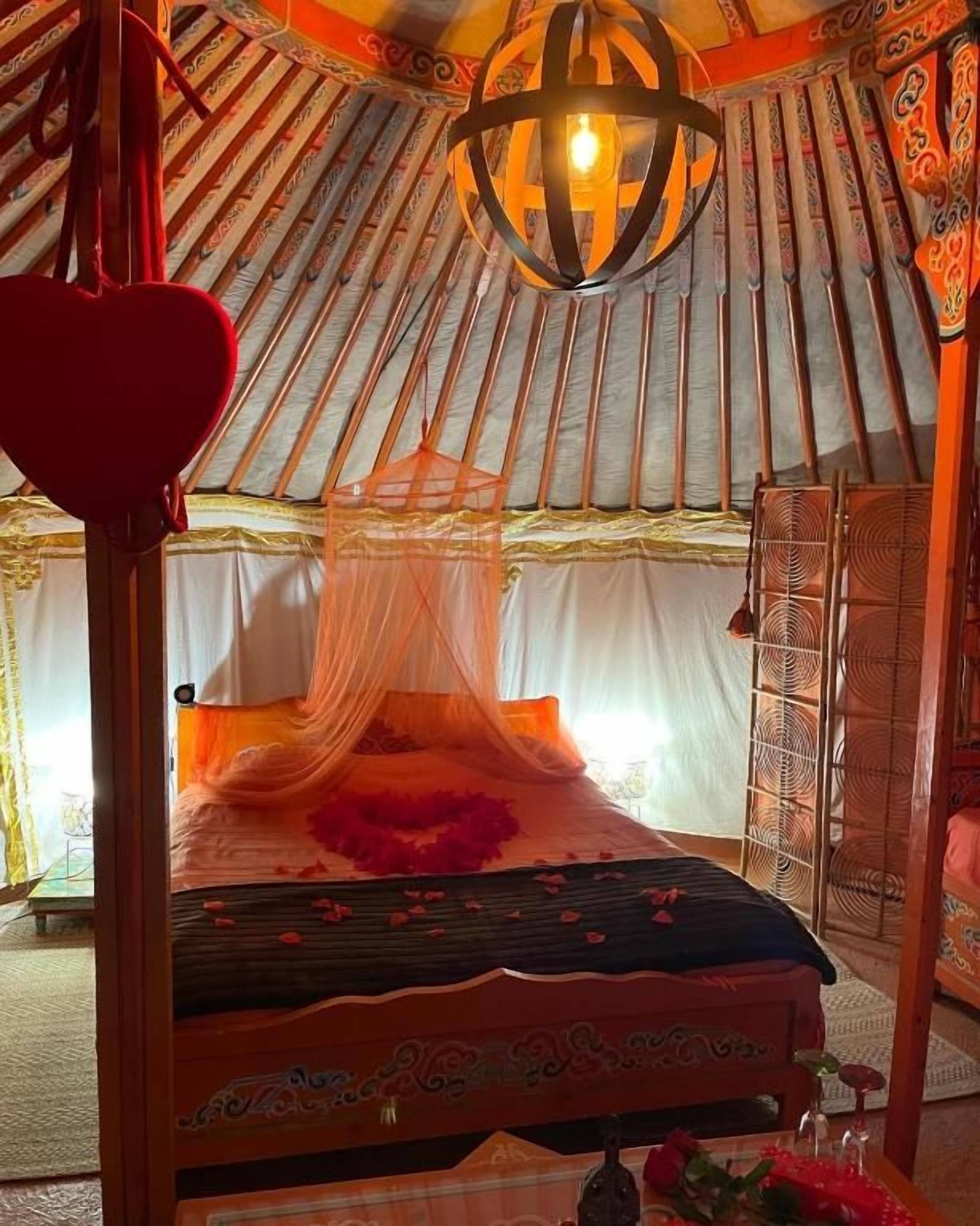 Una cama con dosel, una lámpara colgante y un adorno con forma de corazón.