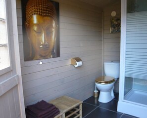 Bathroom features a toilet, wall-mounted toilet paper holder, and a Buddha statue.