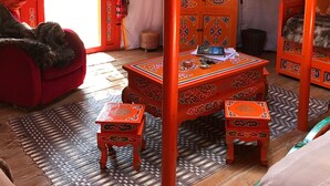 A traditional yurt with a red and white striped roof, a wooden cabinet with intricate carvings, and a small table with a book on it. - Au Soleil Mongol (Sorede)