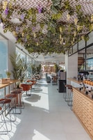 Um café moderno com um balcão comprido, armários de madeira e cadeiras laranja.
