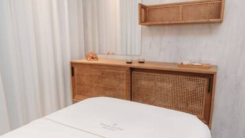 A neatly arranged room with a bed, a wooden console table, and a wicker shelf.