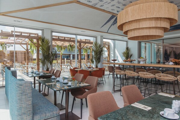 A modern restaurant with glass tables and chairs, wooden beams, and potted plants. - Praia do Sal Lisbon Resort and SPA (Alcochete)